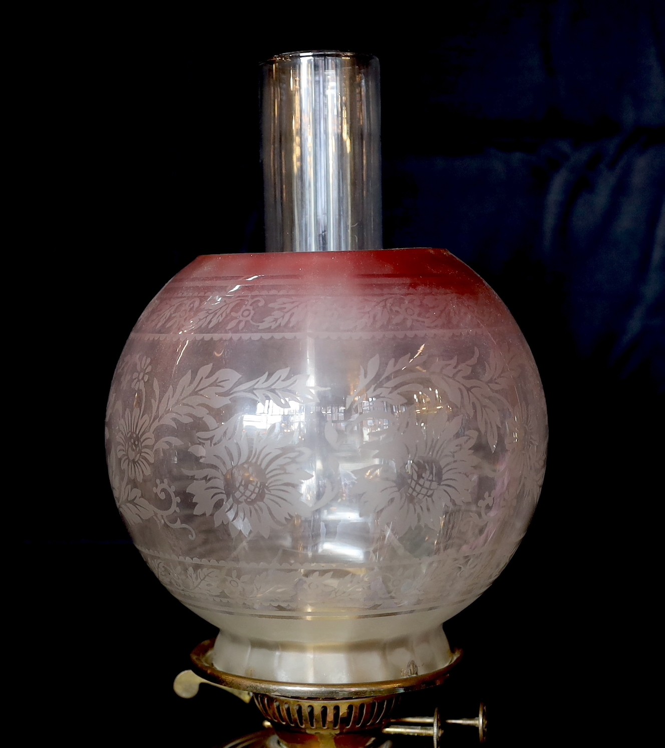 A late Victorian Arts and Crafts wrought iron and brass miniature oil lamp standard, in the manner of Benson, with duplex mechanism and later cranberry tinted glass shade, height without shade 96cm.